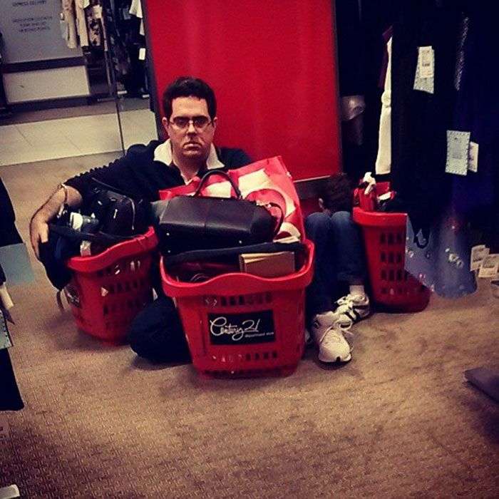 Foto di uomini costretti ad aspettare gli altri mentre fanno shopping