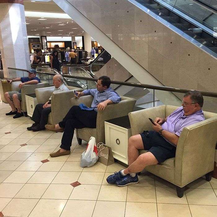Foto di uomini costretti ad aspettare gli altri mentre fanno shopping