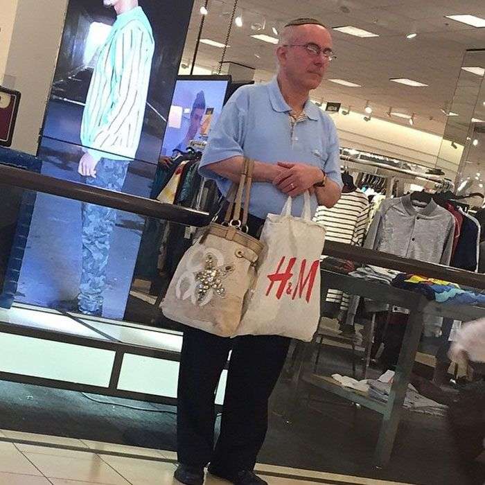 Foto di uomini costretti ad aspettare gli altri mentre fanno shopping